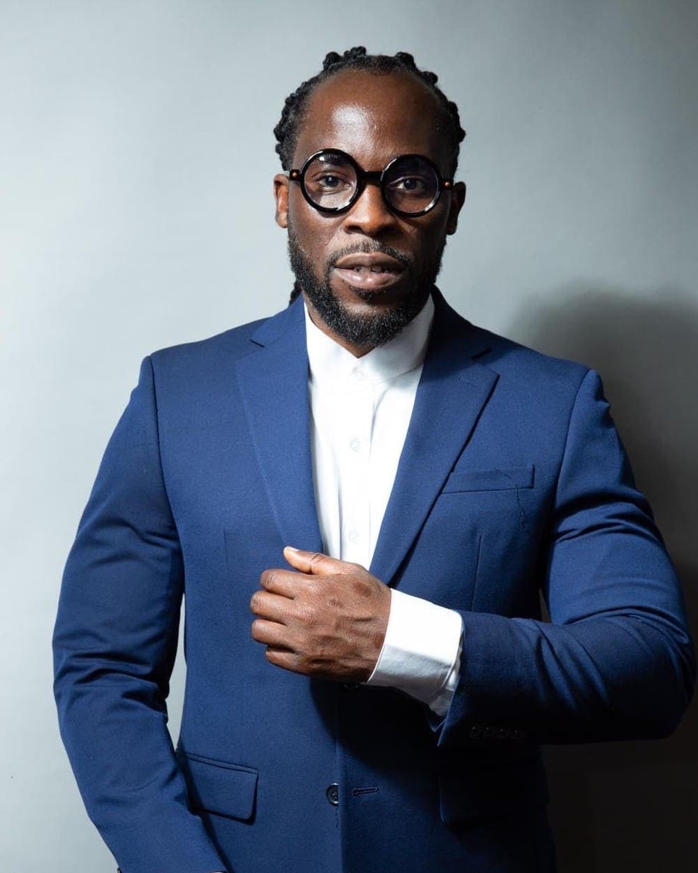 Bobby Digi Olisa, Founder and Executive Director of Canvas Institute, wearing a navy suit and round glasses.
