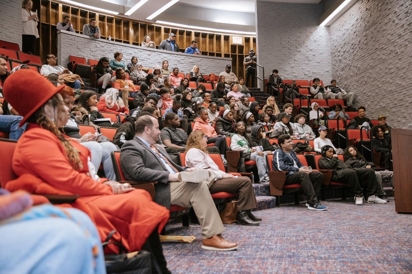 A wide overhead view shows a panel discussion and a full auditorium at the Youth Empowerment Summit.